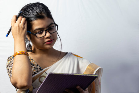 Isolated on white background an Indian office woman in saree writing on notebook with penの写真素材