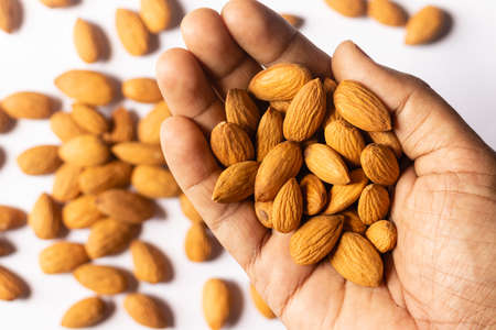 Selective focus on a almond nut held in hand on white backgroundの写真素材