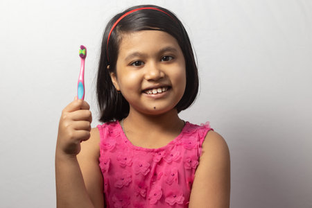 Portrait of an Indian girl child with toothbrush on white backgroundの写真素材