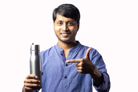 A middle aged Indian man pointing towards a stainless steel bottle in hand on white backgroundの写真素材