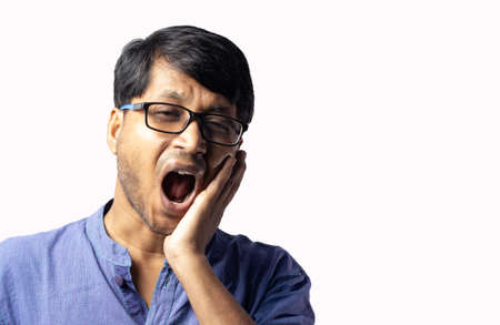 Close up of a young Indian male in blue dress facing teeth problem on white background
