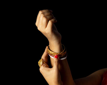Close up of bangles in an Indian hand on black background