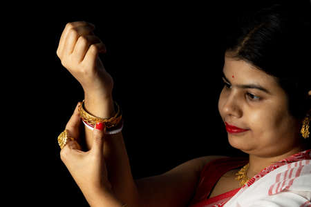 An Indian woman in red saree wearing bangles with smiling face on black background