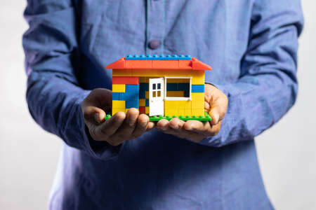 Selective focus on a toy home held in hand by a man on white background