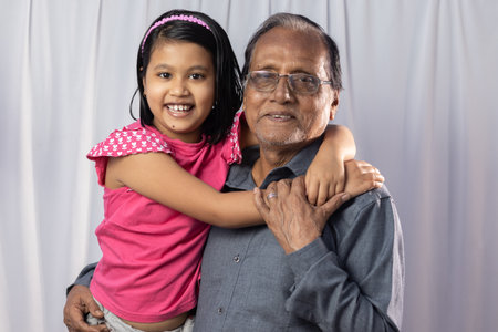 An Indian girl child with her grand father smiling on white background