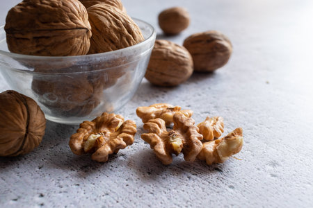 Selective focus on walnuts in a bowl and kernels on white backgroundの写真素材