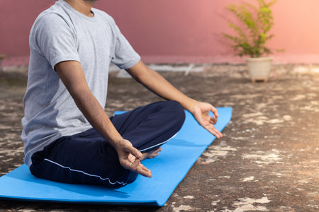An unidentifiable Indian male practicing yoga on yoga mat outdoorsの写真素材
