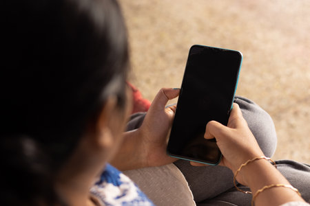 An Indian woman with smart phone looking at blank black screen in hand at home