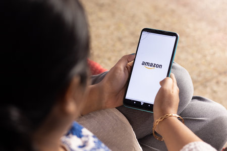 Birbhum, West Bengal, India - December 27th 2022: An Indian woman with smart phone looking at Amazon online shopping site at homeのeditorial素材