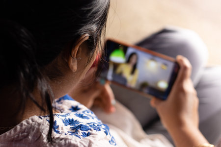 An Indian woman with smart phone enjoying online content at homeの写真素材