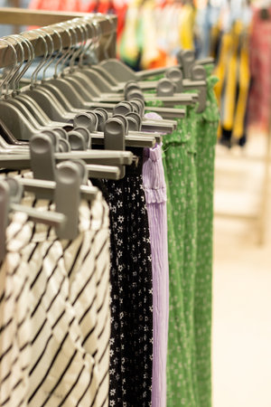 Selective focus on garments hanging from hangers in a shopping mall