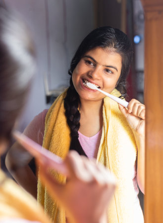 An Indian woman female girl in front of mirror brushing teeth with smiling faceの写真素材