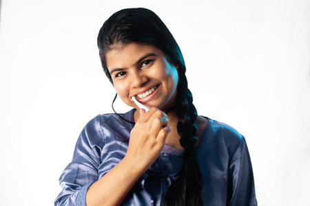 An Indian woman female girl brushing teeth on white background with smiling faceの写真素材