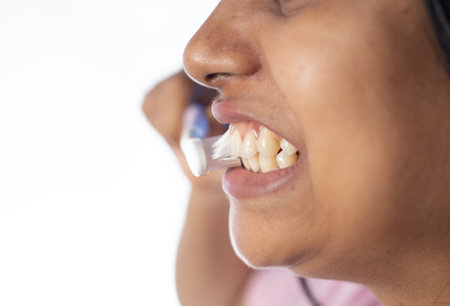 Close up side face of an Indian woman female girl brushing teeth on white background