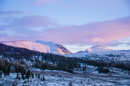 The pink sunset light on the mountains and clouds in winterの写真素材