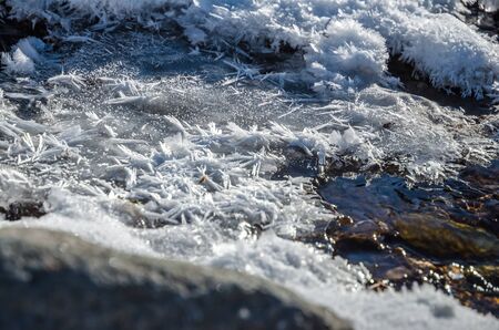 Hoarfrost and grey ice on a winter creekの写真素材