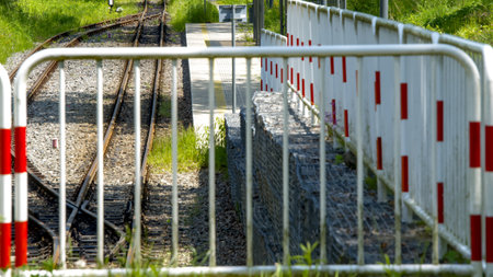 Railway barrier with red and white stripes on a green meadowの写真素材