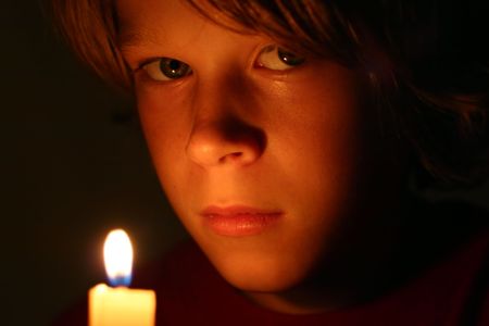 serious boy lit by candlelightの写真素材
