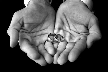 the groom holds his wedding rings in his outstretchs handsの写真素材