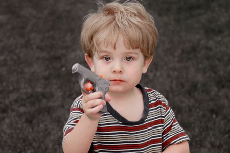 A young boy displays a water gun to the cameraの写真素材