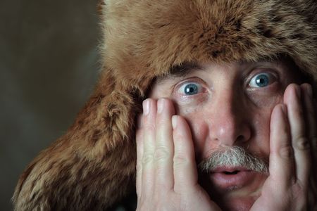 A middle aged man has an astonished look on his face while wearing  a fur hatの写真素材
