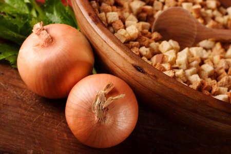 Closeup of a wooden bowl with dried bread croutons ready to be made into dressing or stuffing, other ingredients, onions and celery,  lay next to the bowlの写真素材
