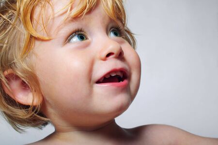 Smiling young boy looks up at someone
