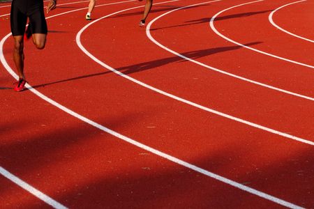 people rounding the curve in a race on a red track