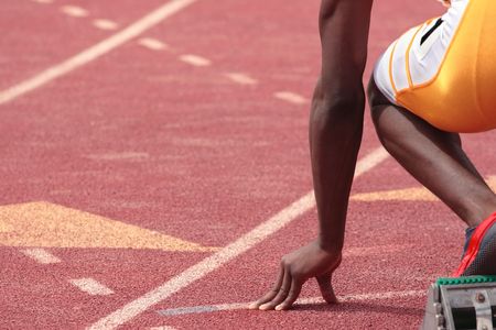 A sprinter in a track and field race is poised at the starting line waiting for the startの写真素材