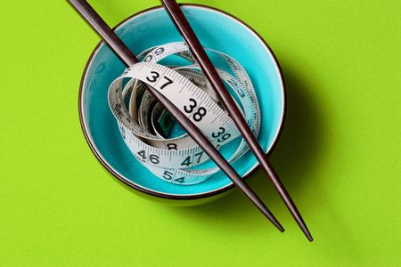 A light blue bowl on Green Background with a tape measure and chopsticksの写真素材