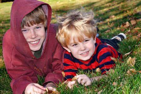 Two boys laying on the ground and smilingの写真素材