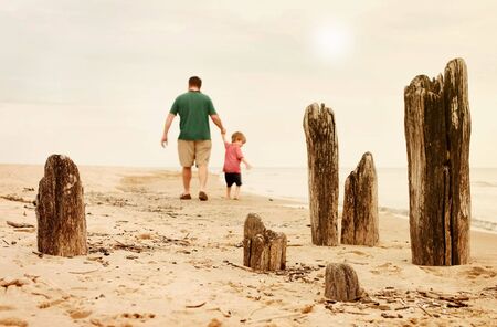 A father and son take a walk along the shore on a foggy afternoon