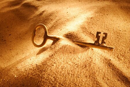 An old key laying in the sandの写真素材