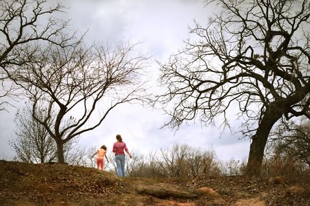a mother and daughter walk on a tree covered dune