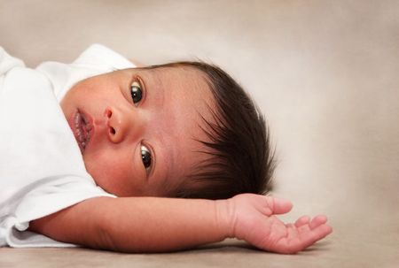 An alert multiracial baby laying on it's back