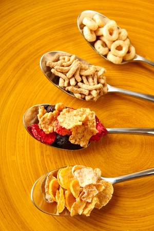 Four spoons that are filled with four types of Breakfast cereal