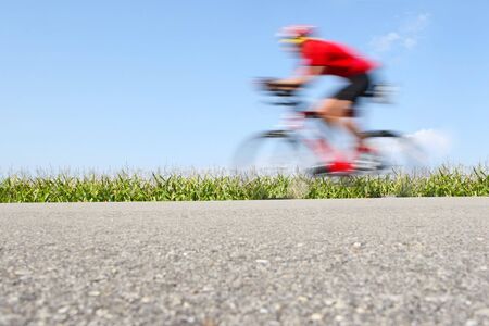 A bicyclist speeds by on a country roadの写真素材