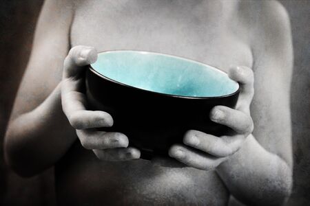 a young boy holds out an empty bowl の写真素材