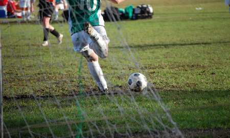 Goal kick at a soccer match with the goal net in the foregroundの写真素材