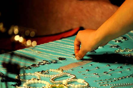 A person choosing a necklace to try on.