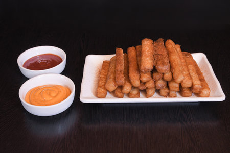 Crispy potato fries served on white rectangular plate with ketchup and mayonnaise in small bowls front angle viewの写真素材