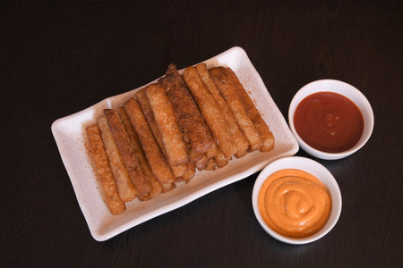 Top view of crispy potato fries served on white rectangular plate with ketchup and mayonnaise in small bowlsの写真素材