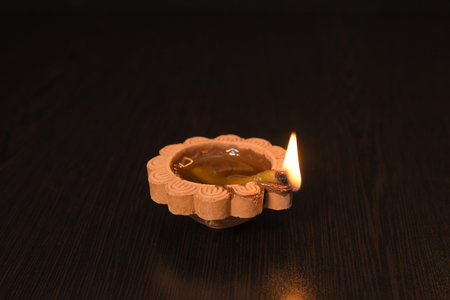 Single lighted clay Diya on dark background symbolizing hope, peace, and Indian festival tradition