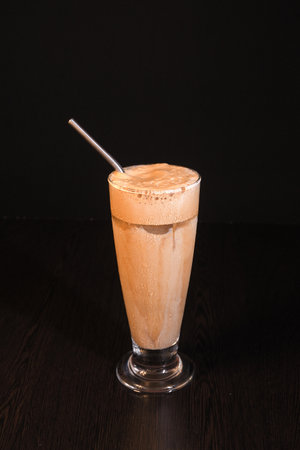 Front upper view of cold coffee in large glass with steel straw and creamy coffee foam on topの写真素材