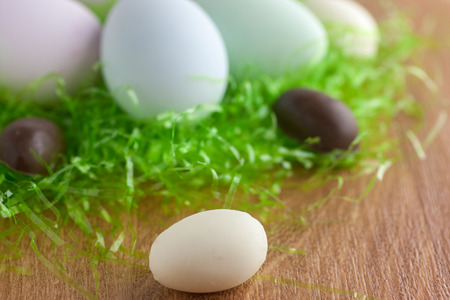 Chocolate, White Chocolate, and colored Easter Eggs in a Green grass nest.