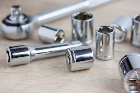 Assorted size sockets laying on a wooden work bench with ratchet.