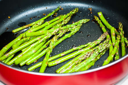 Fresh asparagus cooking in a pan with soy, ginger, and garlic.の写真素材