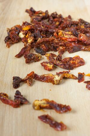 Sun dried tomatoes sliced up on a wooden cutting board.の写真素材