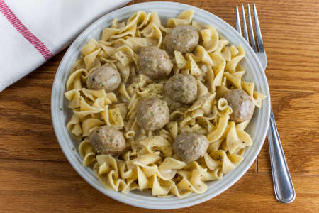 Beef stroganoff made with meatballs on a white plate and wooden table.の写真素材