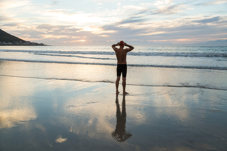 Senior man, aged 65, preparing to swim in the sea at dawnの写真素材